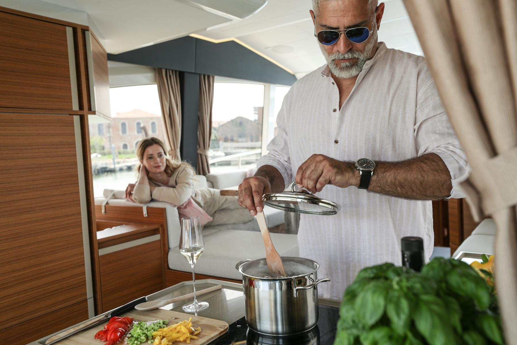Man preparing food in the Greenline 45 Fly galley with a woman seated behind
